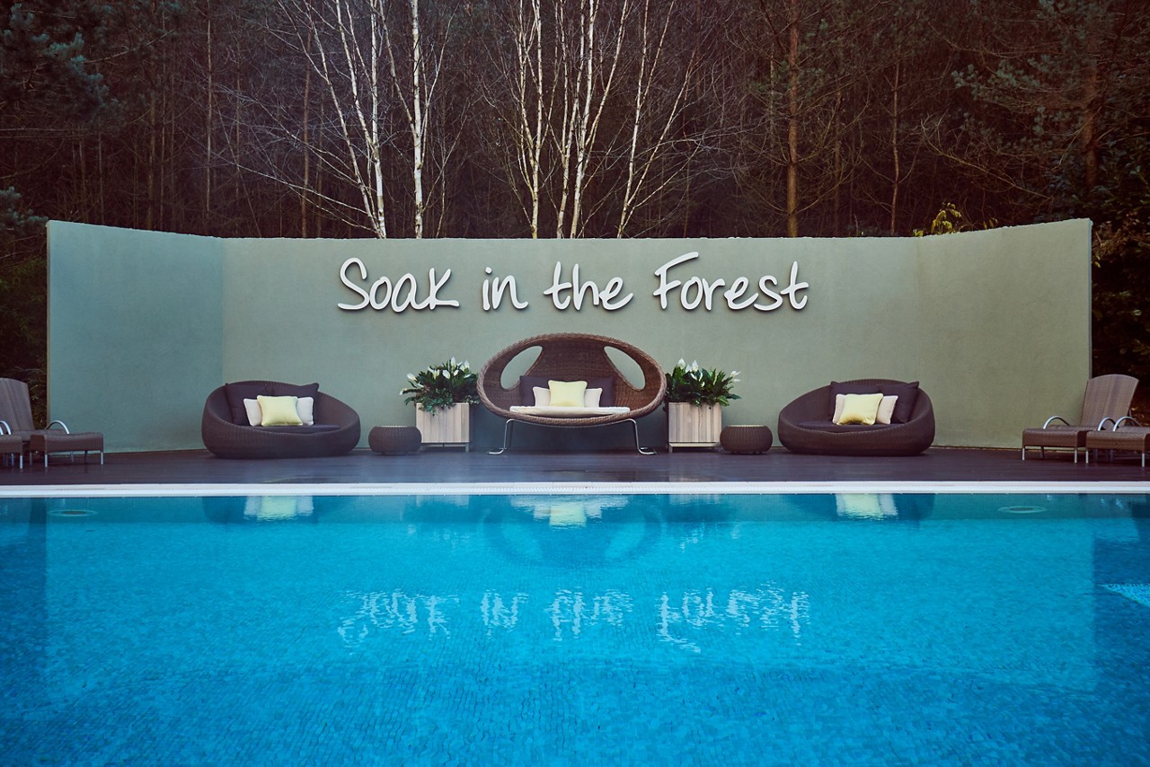 Wooden decking with comfortable seating by an Outdoor Pool in the forest.